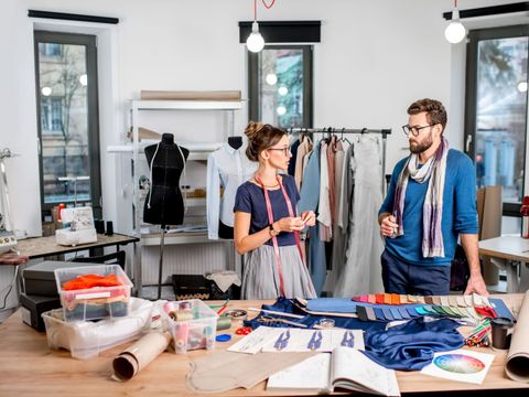 Mann und Frau stehen in einem Atelier für Mode und unterhalten sich.